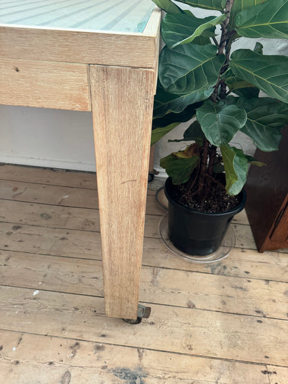 Glass topped table on castors